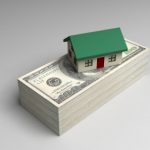 Stack of money with miniature house on top